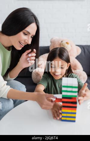 bonne baby-sitter jouer à des blocs de bois jeu avec fille dans le salon Banque D'Images