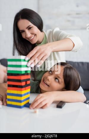 joyeux baby-sitter jouant des blocs de bois jeu avec la fille heureuse dans le salon Banque D'Images