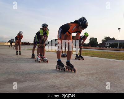 Jeune patineur mixte en ligne tout en s'entraîner sur une piste en plein air au stadion Pacar à Bantul, Yogyakarta, Indonésie. Banque D'Images