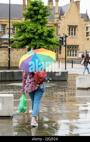 Dame portant un parapluie multicolore ouvert dans le fond de la rue St Marys Lincoln City 2022 Banque D'Images