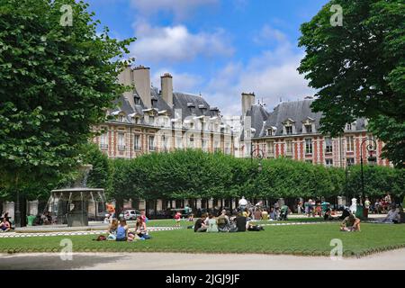 Les familles avec enfants se détendent sur la pelouse des jardins de la place des Vosges lors d'une chaude journée d'été Banque D'Images