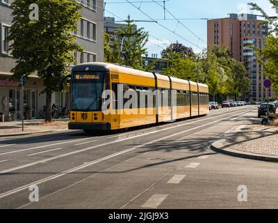 Tram de la DVB dans la ville. Rue vide avec un téléphérique jaune en Saxe. Transports en commun sur les rails. Véhicule de la Dresdner Verkehrsbetriebe. Banque D'Images