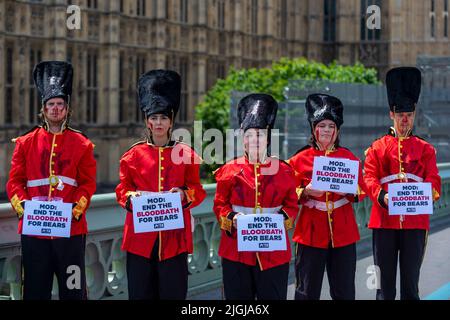 Londres, Royaume-Uni. 11 juillet 2022. Les membres du PETA (People for the Ethical Treatment of Animals) présentent une cascade sur le pont de Westminster vêtus de gardes de la Reine pour se couvrir de faux sang. Le retard de croissance est en avance sur un débat au Parlement au cours duquel les députés discuteront de remplacer par de la fausse fourrure les peaux utilisées pour les casquettes de la Garde reine. Credit: Stephen Chung / Alamy Live News Banque D'Images