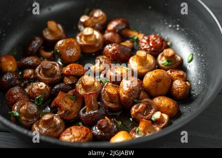 Poêle de champignons frits sur fond de bois sombre. Vue de dessus. Place pour le texte et l'espace de copie. Les champignons sont enrichis d'un grand nombre de Banque D'Images