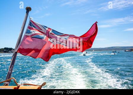 Drapeau rouge soufflant dans le vent sur la poupe d'un bateau Banque D'Images