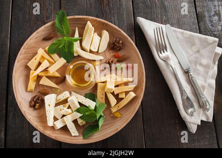 Assiette de fromages avec miel et couverts sur bois Banque D'Images