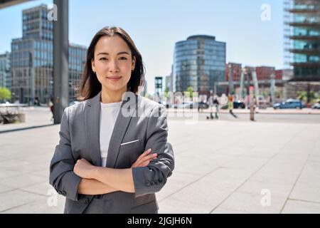 Jeune femme d'affaires asiatique souriante et confiante debout dans la rue, portrait. Banque D'Images