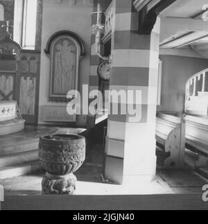 Kyrka intérieur détail avec la police baptismale du 13th siècle en premier plan dans l'église Bräkne-Hoby. Horloge en arrière-plan. Banque D'Images