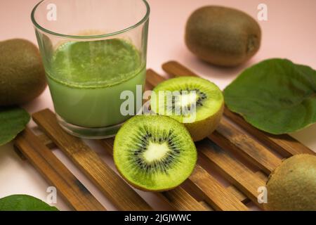 jus de kiwi dans un verre, kiwi coupé en deux et feuilles de kiwi Banque D'Images