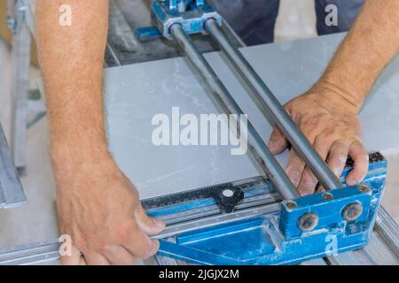 Ouvrier de construction sur plancher de carreaux de céramique découpe à l'aide d'outils manuels pour la pose de carreaux de céramique Banque D'Images