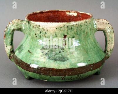 Kruka Pot de faïence, rouge coupé, rond, abdomen élargi avec une bande brune, sous le texte brun abdominal: Kristianopel, deux brasures et trois pattes (pieds). Piplerengobe sous verglas vert semi-transparent extérieur. Bande et texte signés. Intérieur transparent. Dimensions 18,5 x 10 cm. Nonuvingsdiam 107.in acheté le 12/10-1960 chez le marchand d'antiquités Göte Palmlund, Karlskrona. Banque D'Images