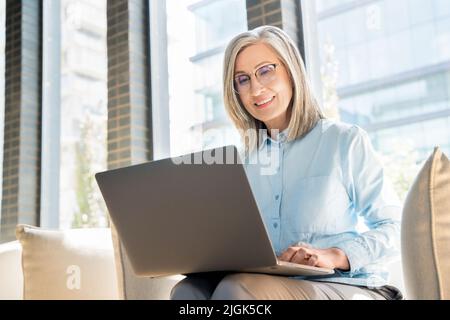 Femme senior travaille comme freelance sur ordinateur portable dans un collègue. Banque D'Images