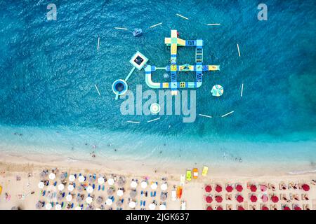 Vue de haut en bas sur une plage avec mer turquoise et un parc de jeux aquatiques flottant Banque D'Images