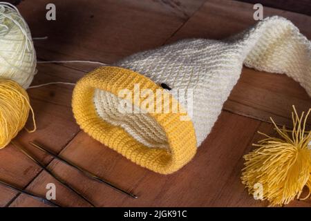 magnifique chapeau d'hiver réalisé par un artisan colombien. chapeau elf tricoté en crochet technique, placé sur une planche en bois avec rouleaux de laine et aiguilles Banque D'Images