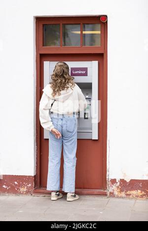 Banque d'Estonie - vue arrière d'une femme qui reçoit de l'argent d'un guichet automatique de la Luminor Bank, Kuressaare, Estonie, États baltes, Europe Banque D'Images