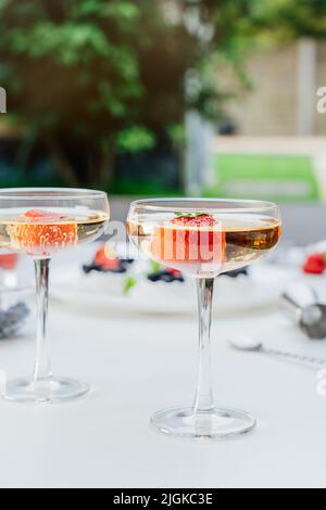 Cocktails avec fraises fraîches et gâteaux de Pavlova à la meringue floue avec fraises fraîches et bleuets sur fond de jardin. Desserts et Banque D'Images