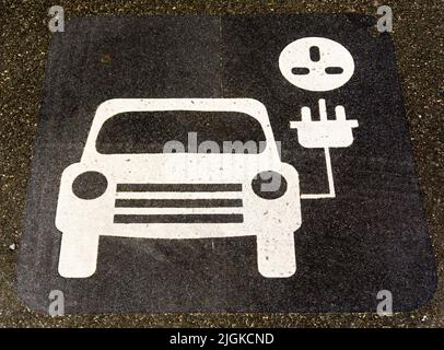 Panneau peint sur l'asphalte de la route dans le parking pour montrer un point de recharge de véhicule électrique. Banque D'Images