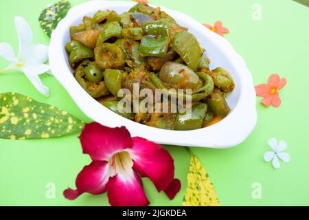 Délicieux cari au poivron vert ou au poivron vert. Remuez avec des oignons sautés sabaji asiatique indien avec du masala. Sur fond rouge, l'image de la nourriture est un espace de copie de Banque D'Images