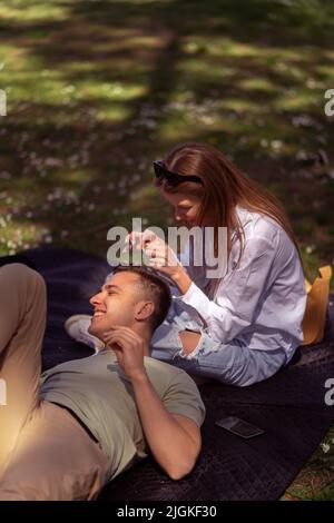 Couple aimant assis sur l'herbe au printemps ensoleillé jour. Banque D'Images