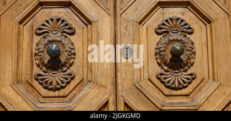 Anciennes portes en bois massif ornées de décorations sculptées à la main par des artistes locaux, dans le splendide centre historique de Lucques Banque D'Images