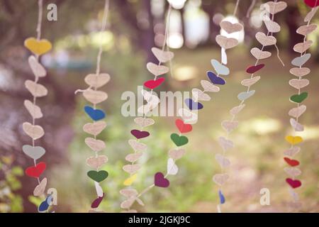 Guirlande de coeurs multicolores en carton sur fond flou. Histoire d'amour ou concept de Saint-Valentin. Bannière, papier peint ou carte postale. Nature Banque D'Images