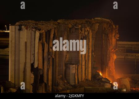 Beyrouth, Liban. 11th juillet 2022. Un feu est vu brûler aux silos à céréales au port de Beyrouth, au Liban, sur 11 juillet 2022. Les silos ont été détruits le 4 août 2020, lorsque plus de 2 500 tonnes de nitrate d'ammonium ont explosé, ce qui a tué au moins 200 personnes et en a blessé des milliers, près des silos. Le gouvernement a décidé en avril qu'il démolirait les silos, malgré les appels aux préserver comme site commémoratif. (Image de crédit : © Daniel Carde/ZUMA Press Wire) Banque D'Images