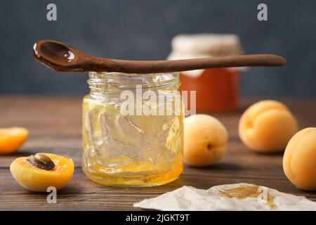 Vider le pot de confiture d'abricot mangée. Vider le pot en verre de confiture d'abricot maison, une cuillère et des fruits abricot mûrs sur une table de cuisine. Banque D'Images