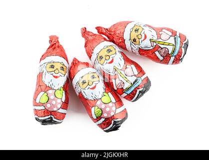 Groupe de figurines de père noël au chocolat enveloppées dans une feuille isolée sur fond blanc Banque D'Images