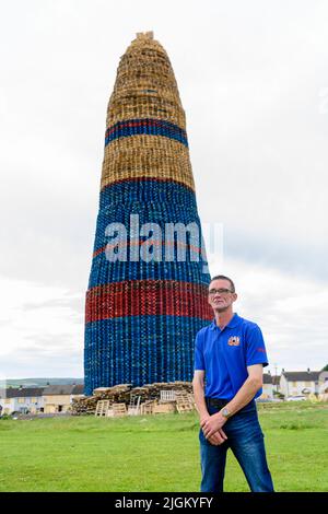 Larne, Irlande du Nord, Royaume-Uni, Royaume-Uni. 11th juillet 2022 - Un membre du comité des feux de camp se tient à côté du feu de camp de Craigyhill, qui a été officiellement déclaré le plus haut du monde à une hauteur de 203 pieds (61,8m) Banque D'Images