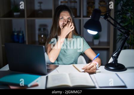 Une adolescente qui fait ses devoirs à la maison tard dans la nuit sentait quelque chose de stinky et de dégoûtant, une odeur intolérable, tenant l'haleine avec les doigts sur le nez. b Banque D'Images