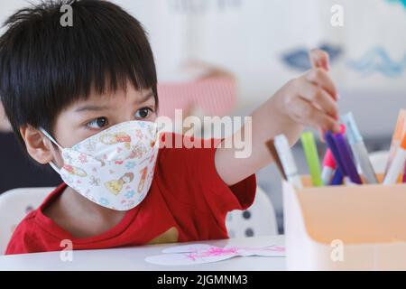 un garçon étudiant qui fait un croche-tête de couleur pour dessiner et peindre en salle de classe à l'école maternelle. éducation préscolaire pour les enfants. Banque D'Images