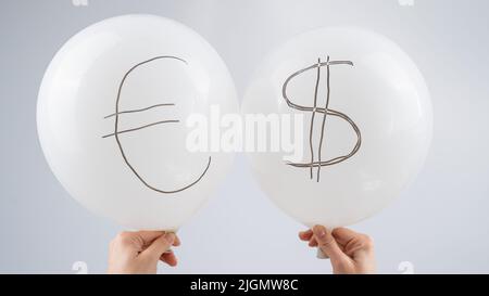 Femme tenant deux ballons blancs avec des symboles dollar et euro. Banque D'Images