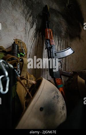 La mitrailleuse du soldat ukrainien se penche contre le mur de la maison, la guerre en Ukraine, les armes et l'armure dans une maison abandonnée. Banque D'Images