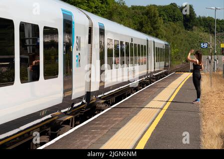 Micheldever, Hampshire, Angleterre, Royaume-Uni. 2022. Une femme agitant de la plate-forme comme un nouveau train de voyageurs South Western Railway part de la gare Miicheldever à Banque D'Images