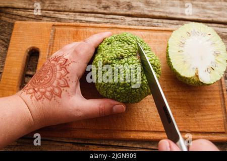 Femme coupant une pomme Adam sur une planche de bois vue du dessus Banque D'Images