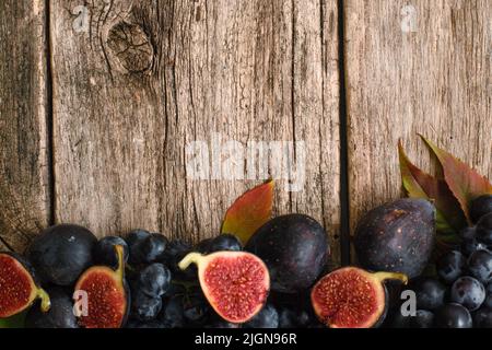 Figues moitiés avec raisin sur bois plat Banque D'Images