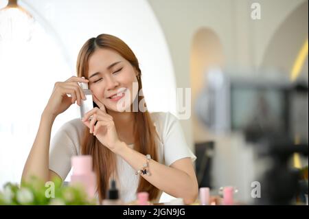 Belle attirante jeune asiatique femme blogueur de beauté faisant une vidéo de transport de beauté et de la revue d'un soin de la peau des produits cosmétiques à ses disciples. Banque D'Images