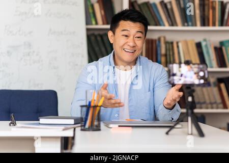 Tuteur masculin japonais ayant cours via appel vidéo sur le lieu de travail Banque D'Images