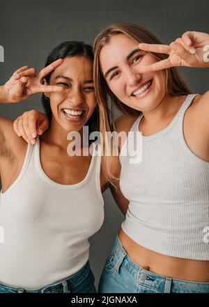 Deux femmes habillées décontractées qui font le symbole de la pièce Banque D'Images