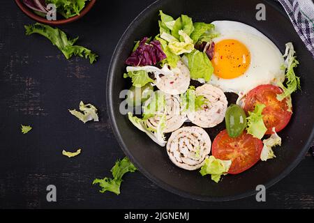 Œuf frit, rouleau de viande, olives et tomates. Keto, petit déjeuner paleo. Menu cétogène. Vue de dessus, plan d'appartement Banque D'Images