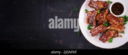 De délicieuses côtes de bœuf grillées sur l'assiette sur fond sombre. Savoureux barbecue de viande. Vue de dessus, bannière Banque D'Images