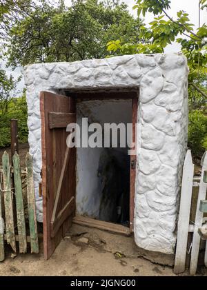 Cave historique à racines d'époque ouverte creusée sous terre dans la campagne, à proximité des arbres Banque D'Images