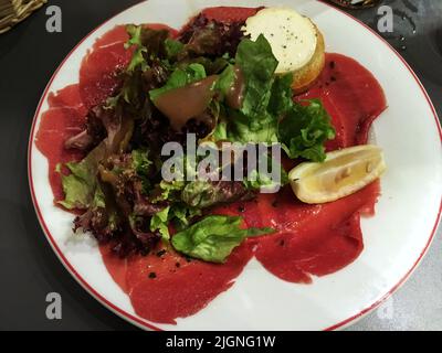 Finement tranché et servi cru, généralement comme un hors-d'œuvre. Le bœuf était servi avec du citron, de l'huile d'olive et du fromage, le délicieux carpaccio. Banque D'Images