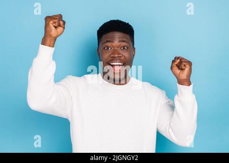 Photo de la belle bonne humeur ectatic homme enthousiaste soulever les poings dans le triomphe isolé sur fond bleu de couleur Banque D'Images
