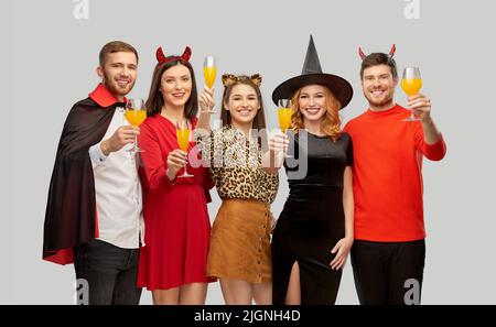 des amis heureux en costumes d'halloween sur gris Banque D'Images