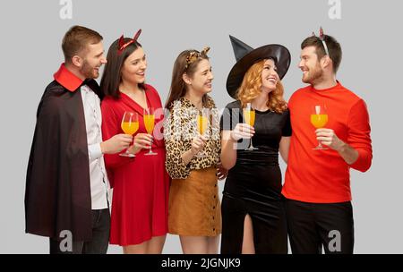 des amis heureux en costumes d'halloween sur gris Banque D'Images