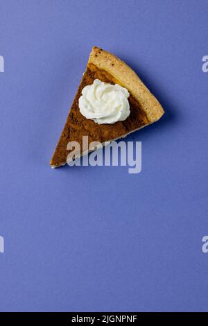 Composition d'un morceau de tarte à la citrouille avec de la crème fouettée sur fond bleu Banque D'Images