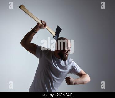 Homme d'apparence caucasienne balance émotionnellement une hache. Photo shoot dans le studio Banque D'Images