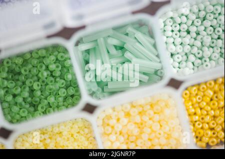 Petites petites perles de verre colorées dans un conteneur en plastique. Vue rapprochée du dessus. Arrière-plan et texture. Banque D'Images