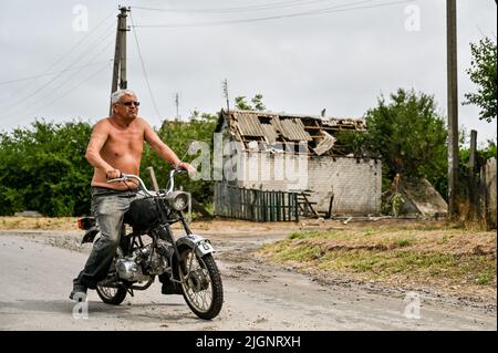 Un homme fait un scooter le long de la route endommagée par les bombardements russes, village de Prymorske, région de Zaporizhzhia, sud-est de l'Ukraine, 11 juillet, 2022. L'Ukraine a mis en garde les habitants du sud de Kherson et de Zaporizhzhia d'évacuer alors qu'elle se prépare à lancer une contre-offensive pour reprendre la zone. Les régions de Kherson et de Zaporizhzhia ont été rapidement occupées par les troupes russes fin février après avoir traversé le pont depuis la Crimée, annexée par la Russie. Photo de Dmytro Smoliyenko/Ukrinform/ABACAPRESS.COM Banque D'Images